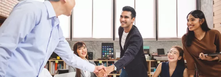 Diverse group of professionals meeting and shaking hands in an office setting.