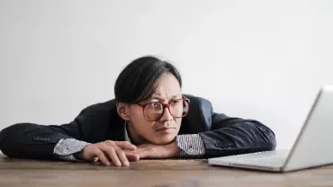 Person in glasses resting head on hands