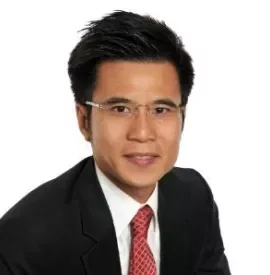 Portrait of a man in a suit and red tie with glasses against a white background.