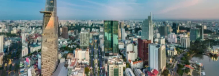 Panoramic view of a city skyline with modern high-rise buildings and a river at sunset.
