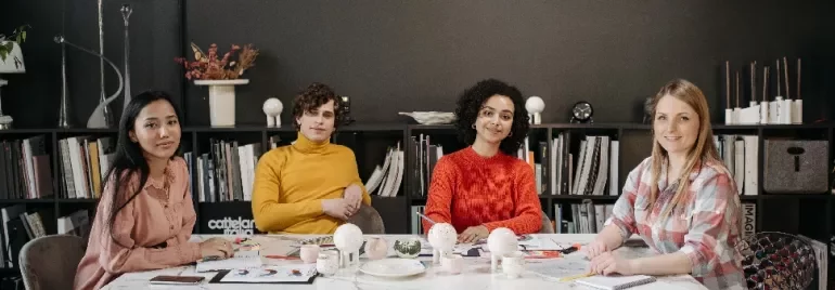 Four people sitting at a conference table with bookshelves in the background.