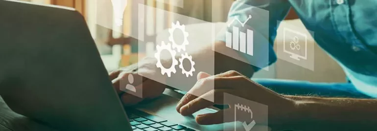 Hands typing on a laptop with overlay icons of gears and graphs.