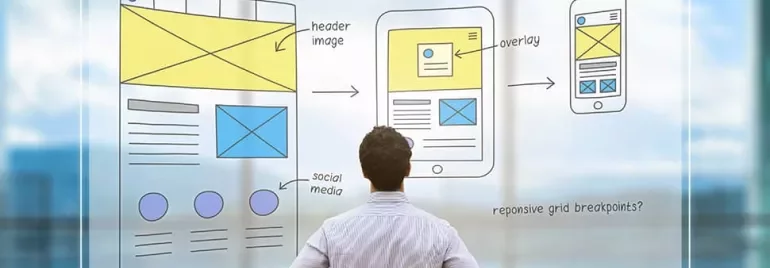 Man looking at sketches of responsive web design layouts on glass board.
