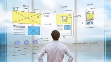 Man looking at sketches of responsive web design layouts on glass board.