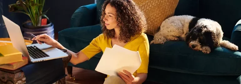 Woman working on laptop with papers