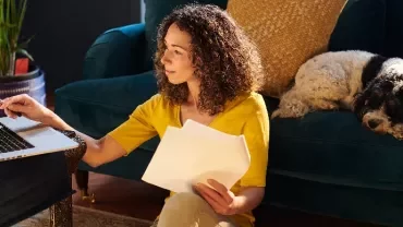 Woman working on laptop with papers