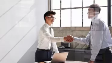Two people shaking hands in a bright office