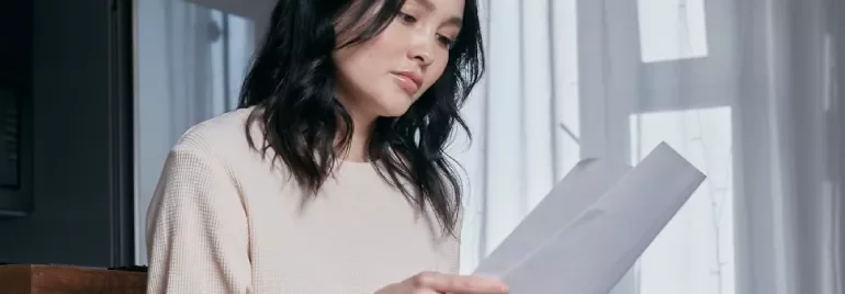 Woman sitting and reading a document by a window