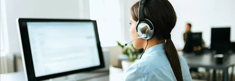 Person with a headset working at a desktop computer.