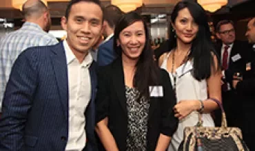 Three people smiling at a social event with warm lighting.