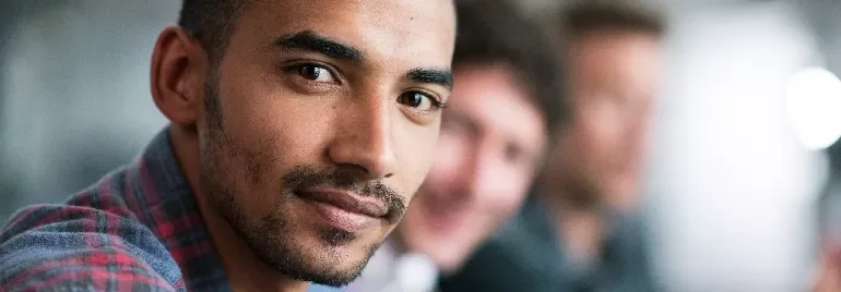 Portrait of a man in focus with two others blurred in the background.