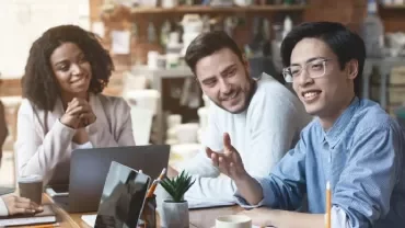 Diverse group having a casual meeting at a cafe with laptops and coffee.