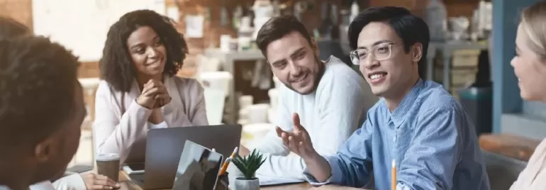 Diverse group having a casual meeting at a cafe with laptops and coffee.