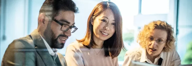 Three colleagues smiling and collaborating on a project