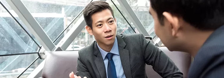 Two businessmen in discussion inside a modern office building.
